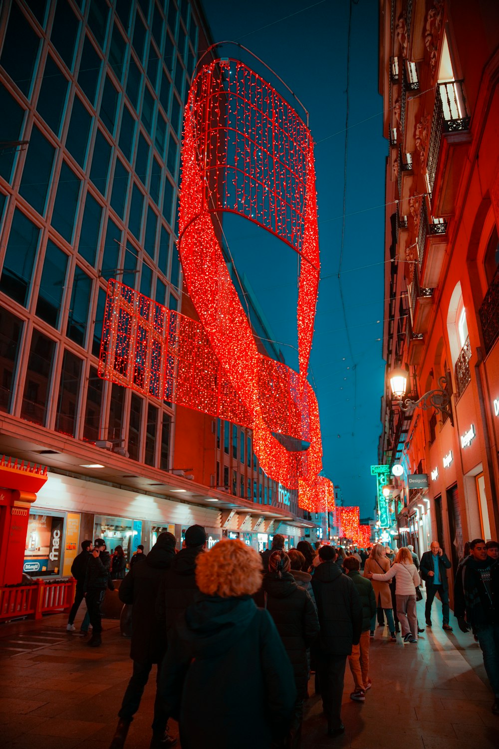 a group of people walking down a street next to tall buildings