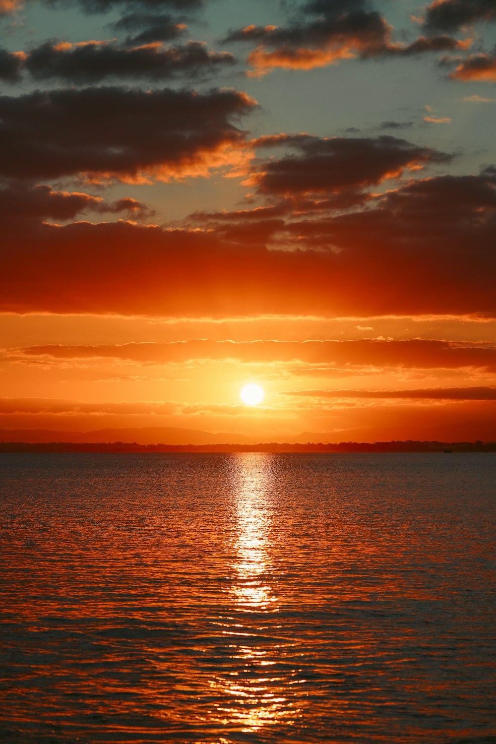 a large body of water with a sunset in the background