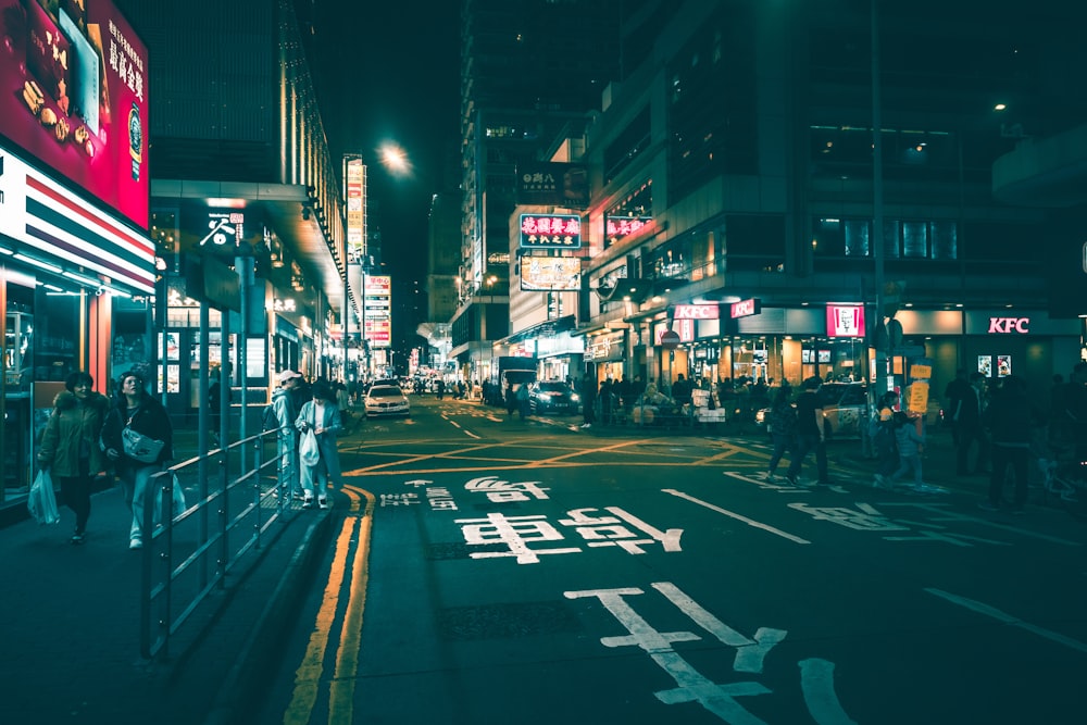 a city street at night with people walking on the sidewalk