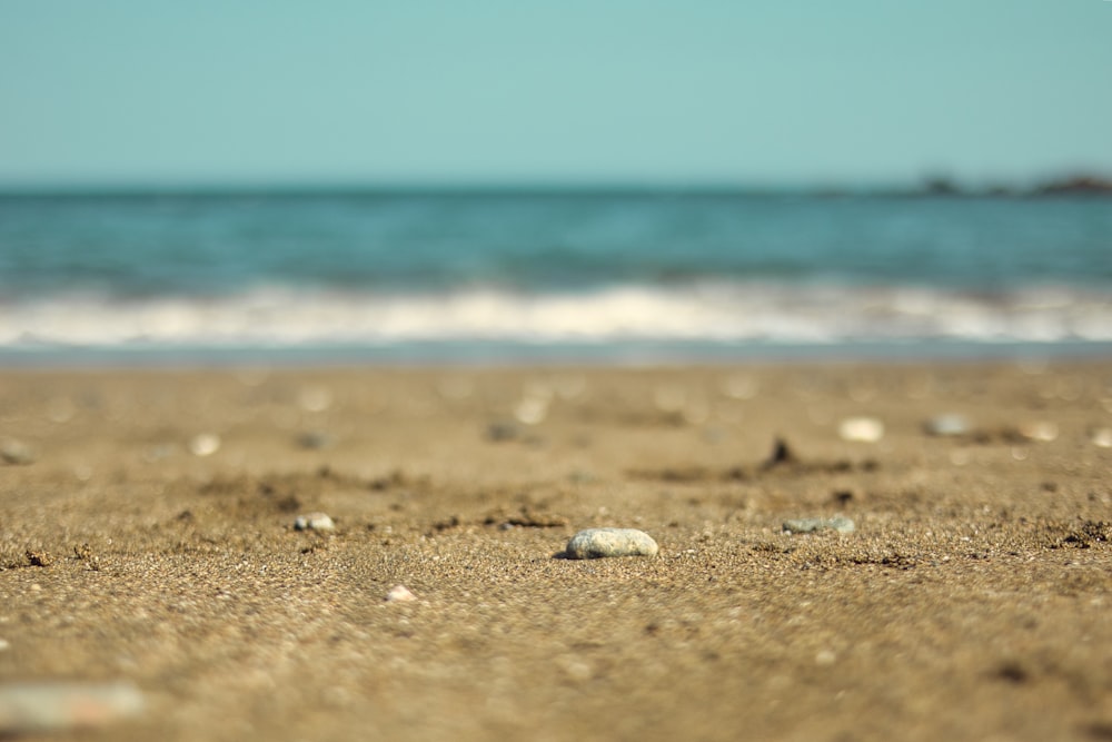 a sandy beach with rocks and water in the background