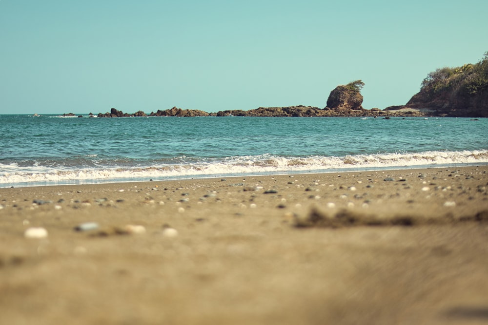 a view of a beach with a rock outcropping in the distance