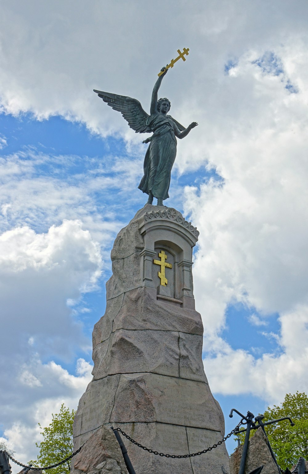 a statue of a woman holding a cross on top of a rock