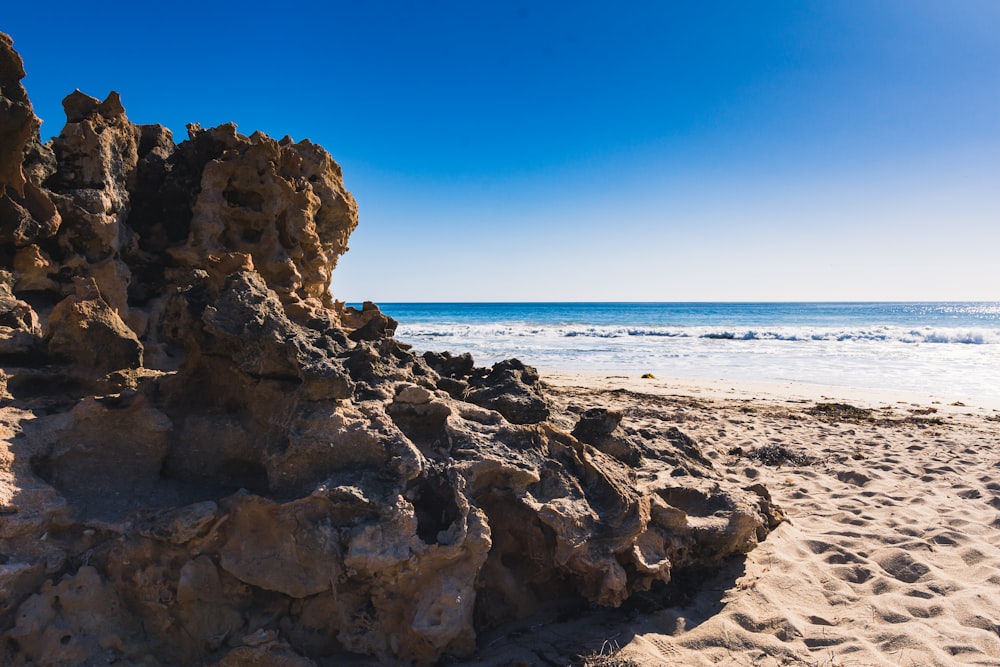 a rock formation on a beach with the ocean in the background