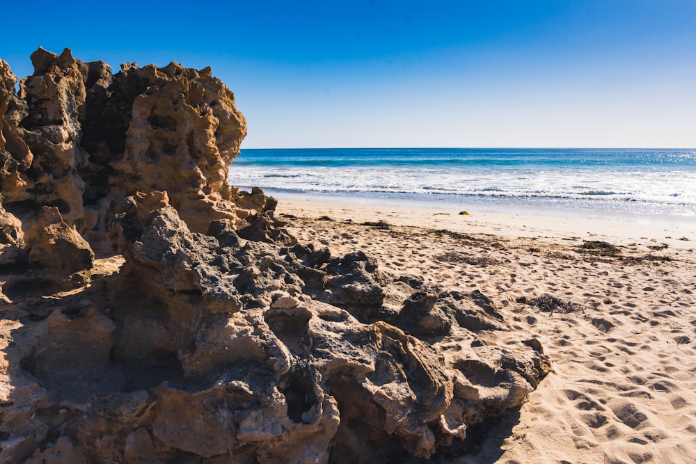 a rock formation on a sandy beach next to the ocean