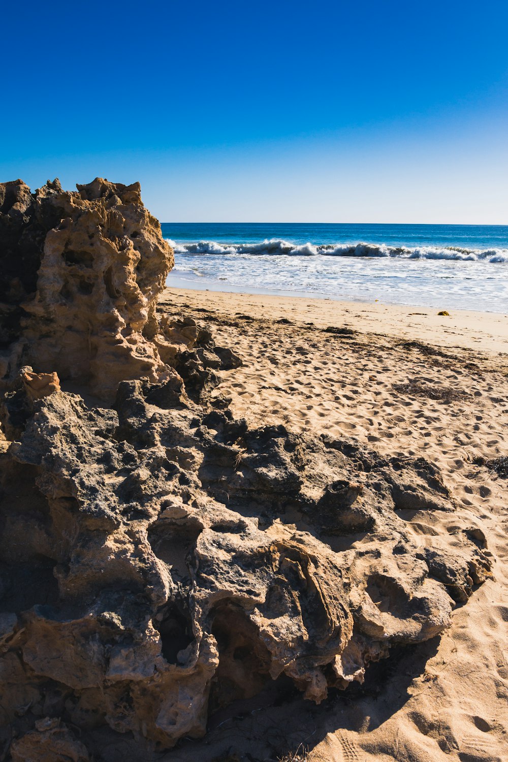 a rock formation on a sandy beach next to the ocean