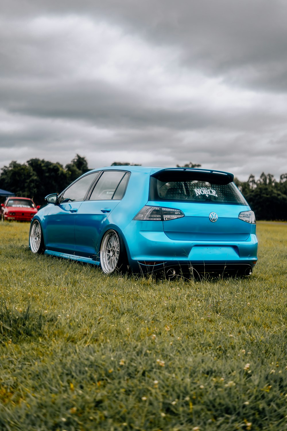 a blue car parked in a grassy field