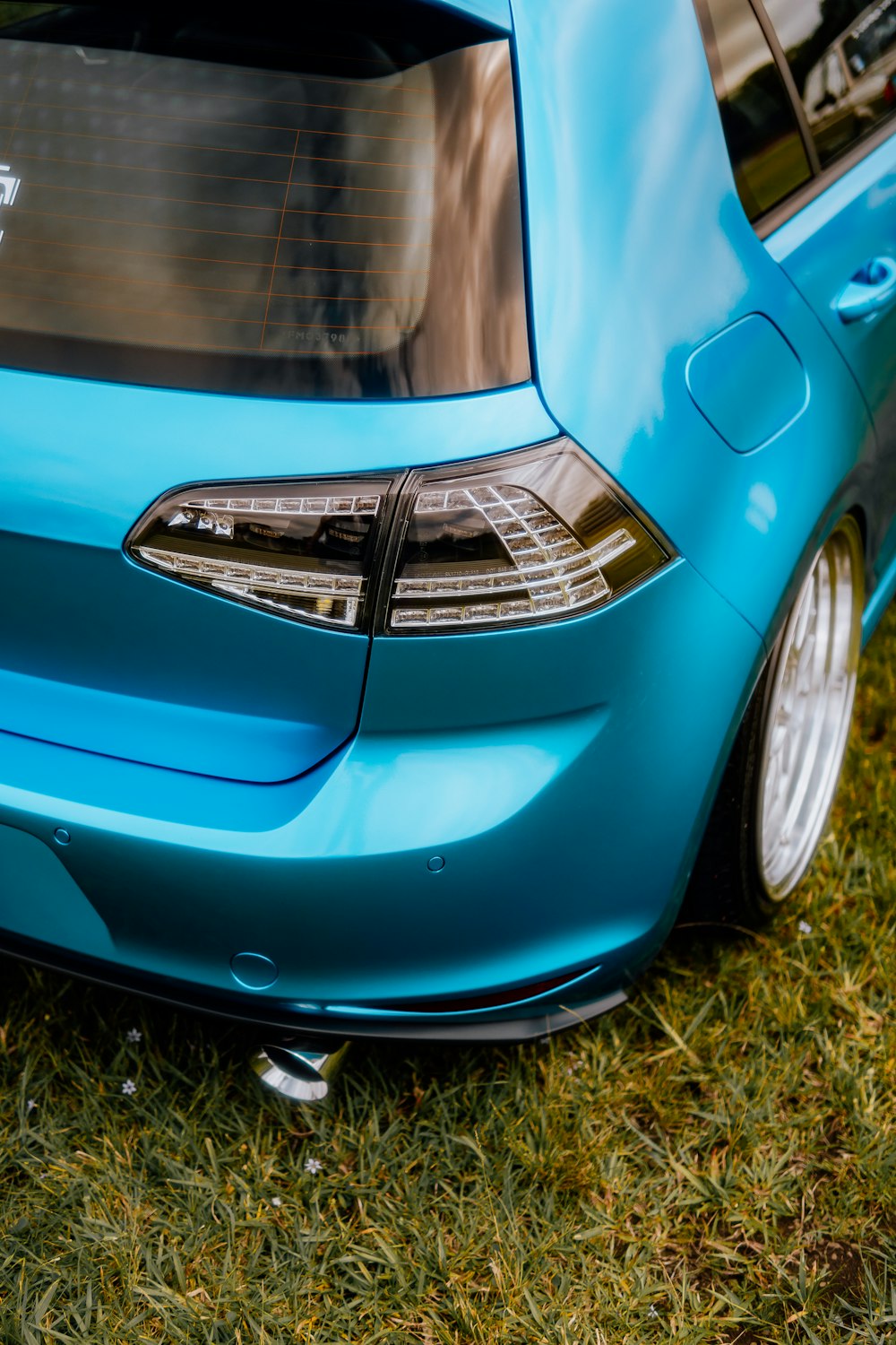 a blue car parked on top of a lush green field