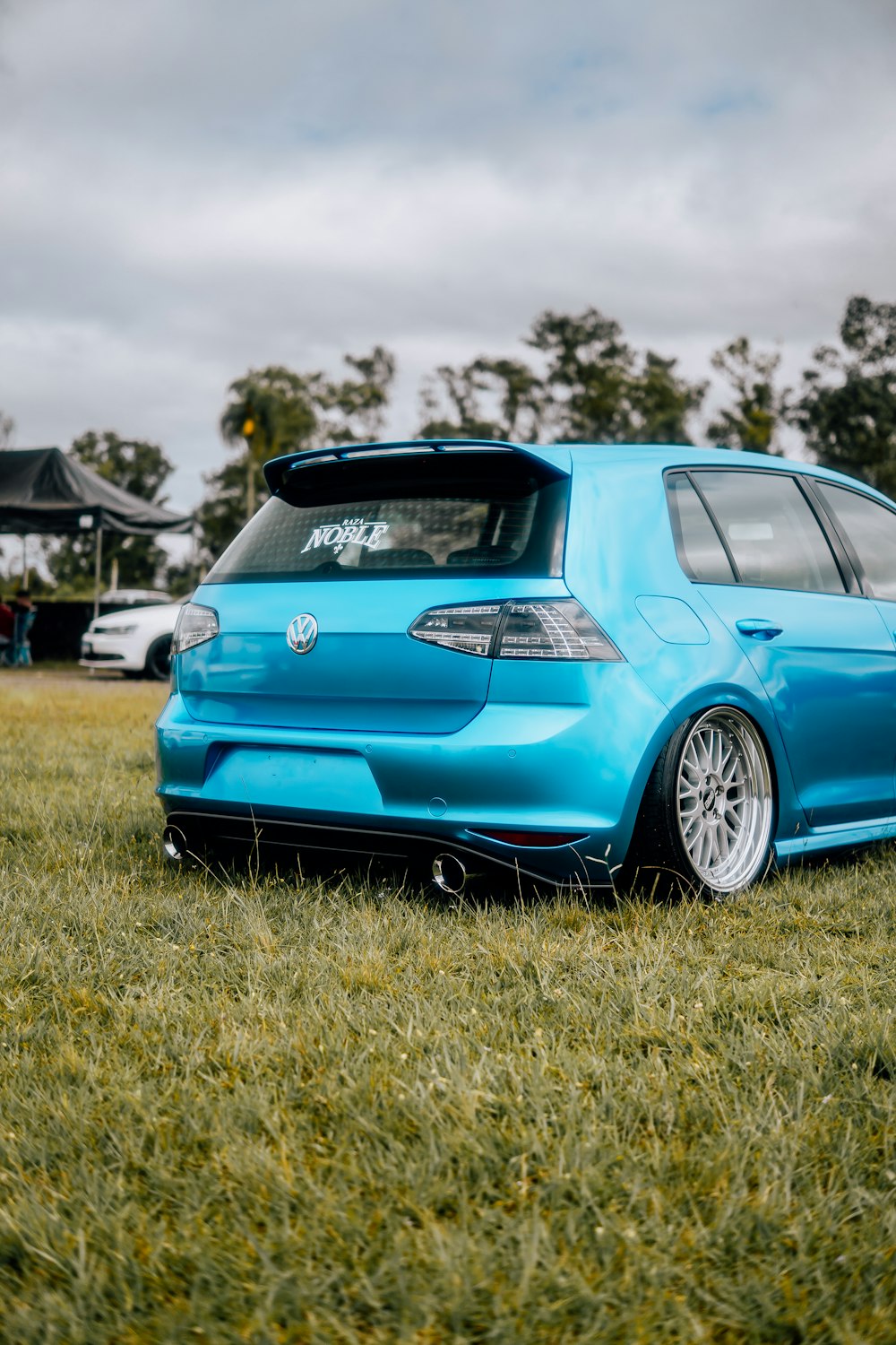 a blue car parked on top of a lush green field