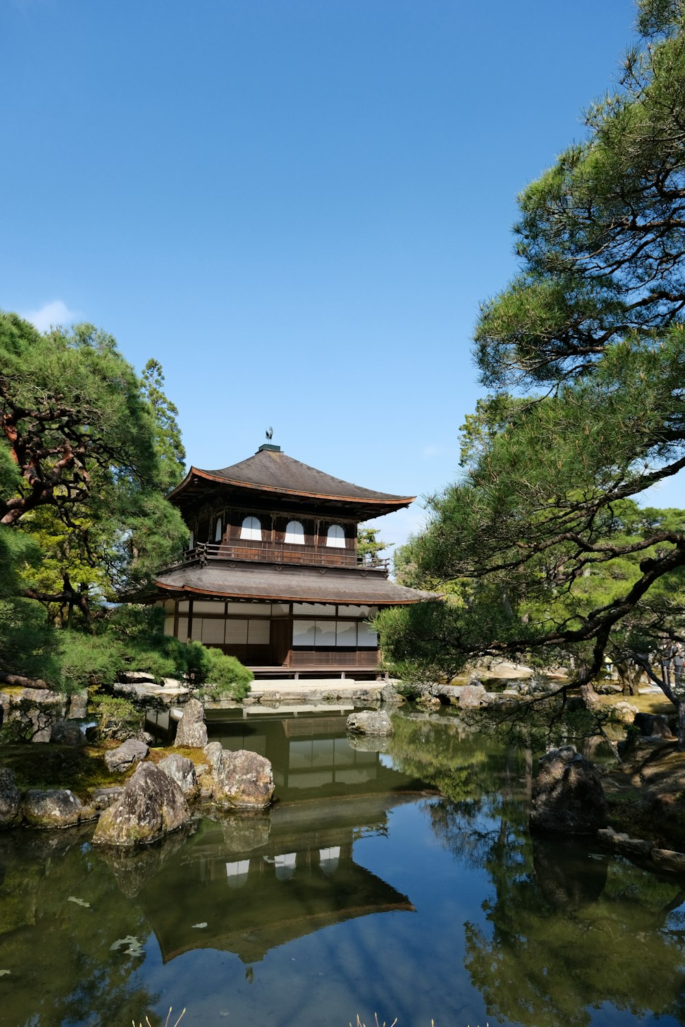 Une pagode au milieu d’un étang entouré d’arbres