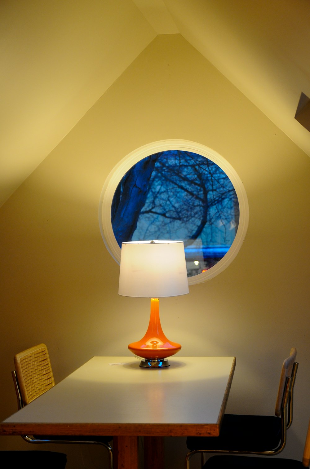 a table with a lamp and a round window