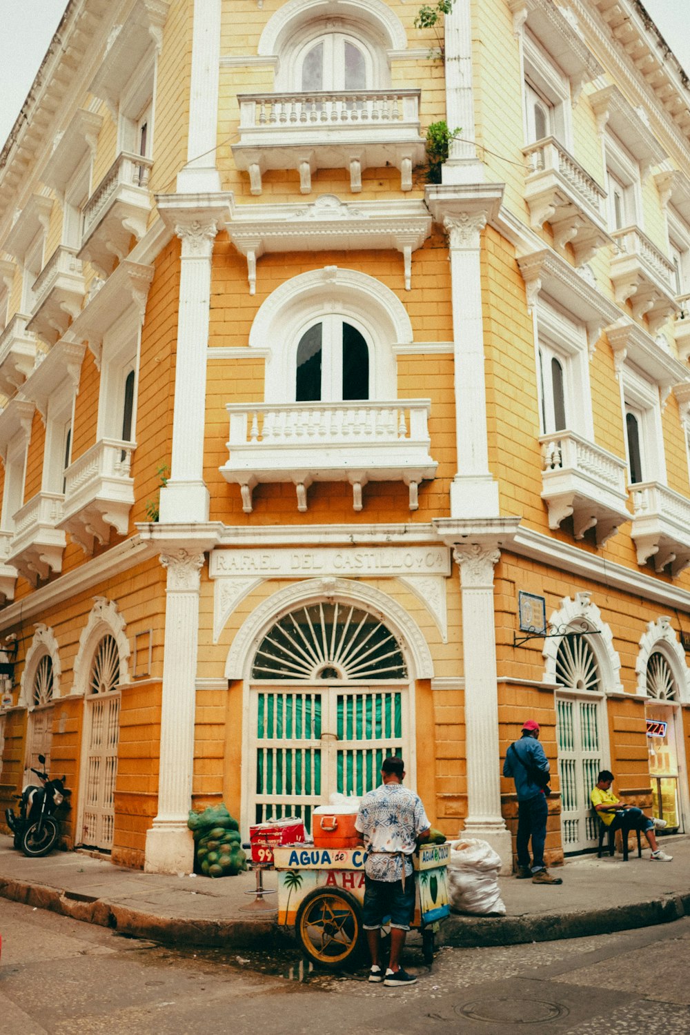 a yellow and white building with people standing outside of it