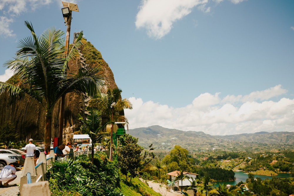 a group of people walking up a hill next to a lush green hillside