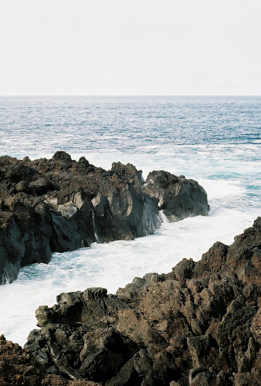 a person standing on a rocky shore next to the ocean