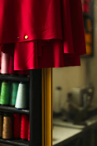 a red dress hanging on a rack with spools of thread