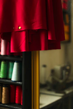 a red dress hanging on a rack with spools of thread