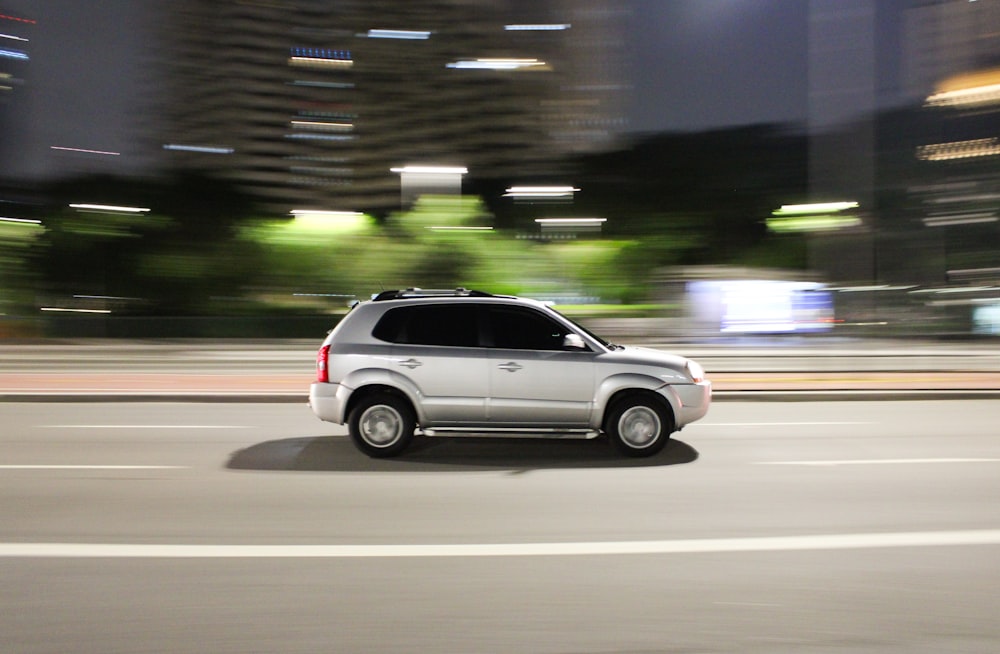 a white suv driving down a city street at night