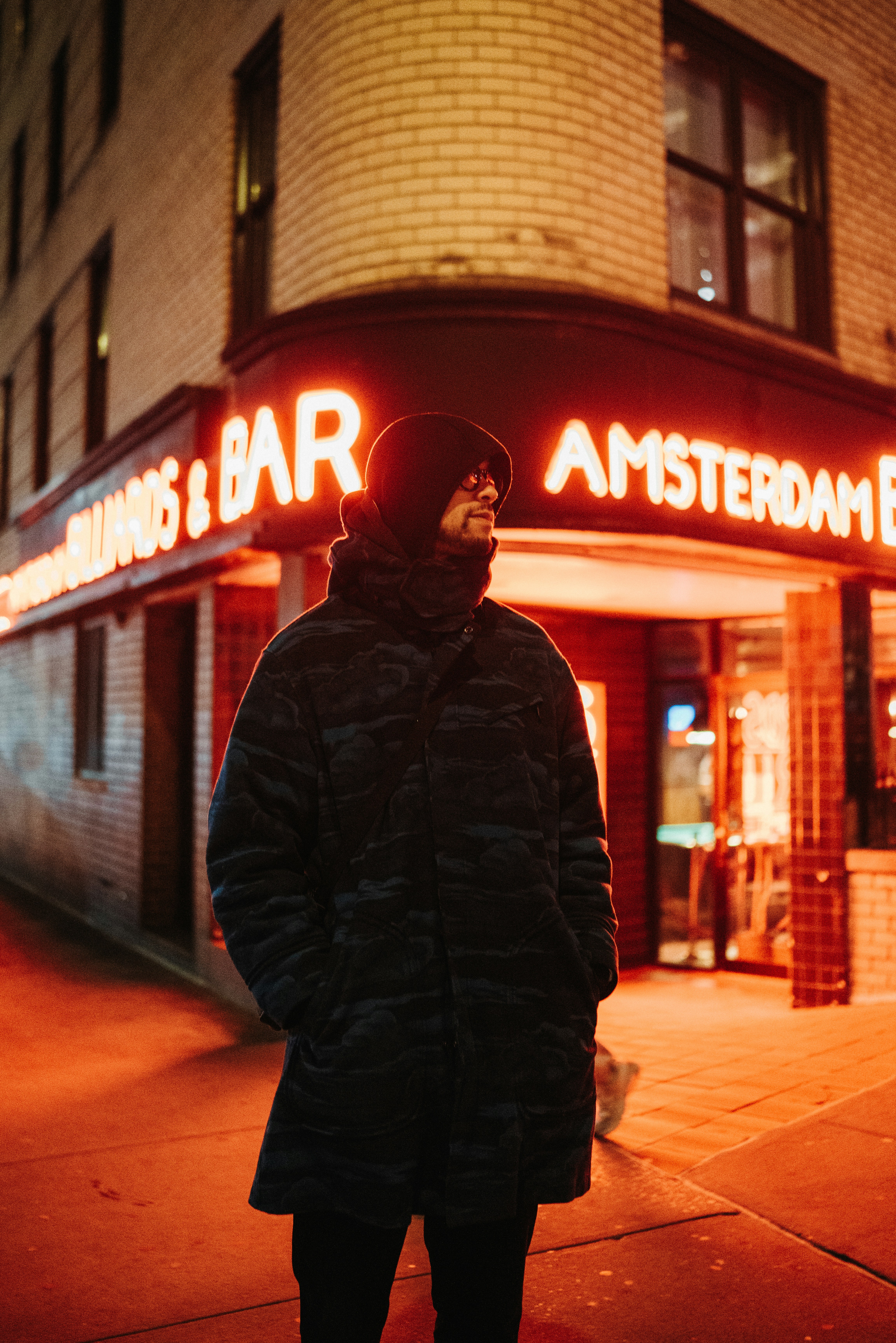 a man standing on a sidewalk in front of a bar