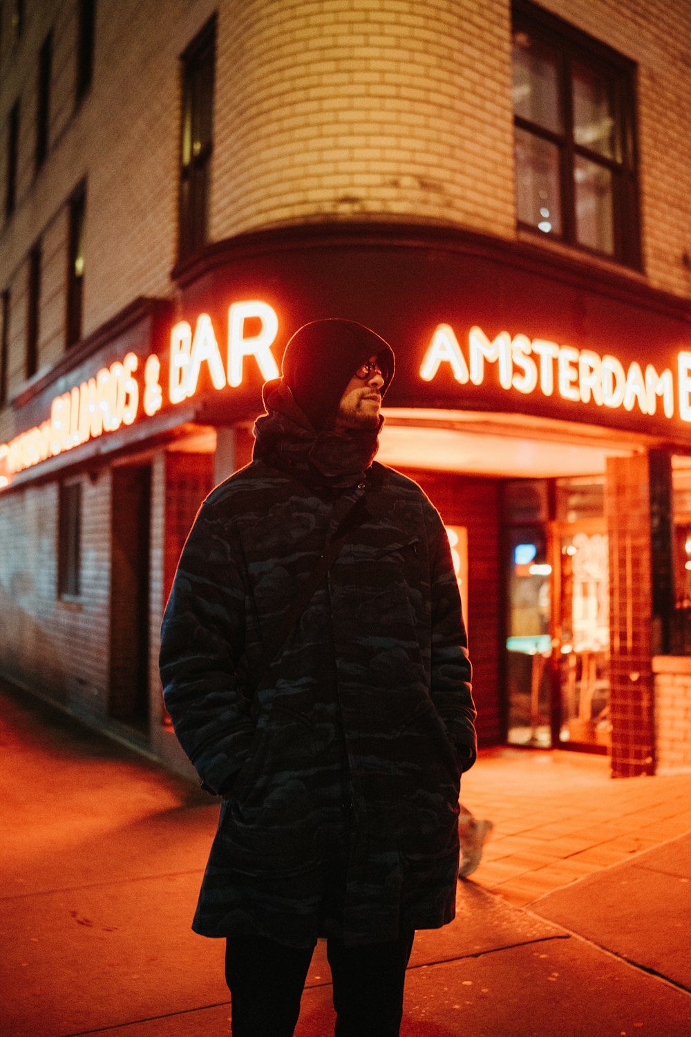 a man standing on a sidewalk in front of a bar