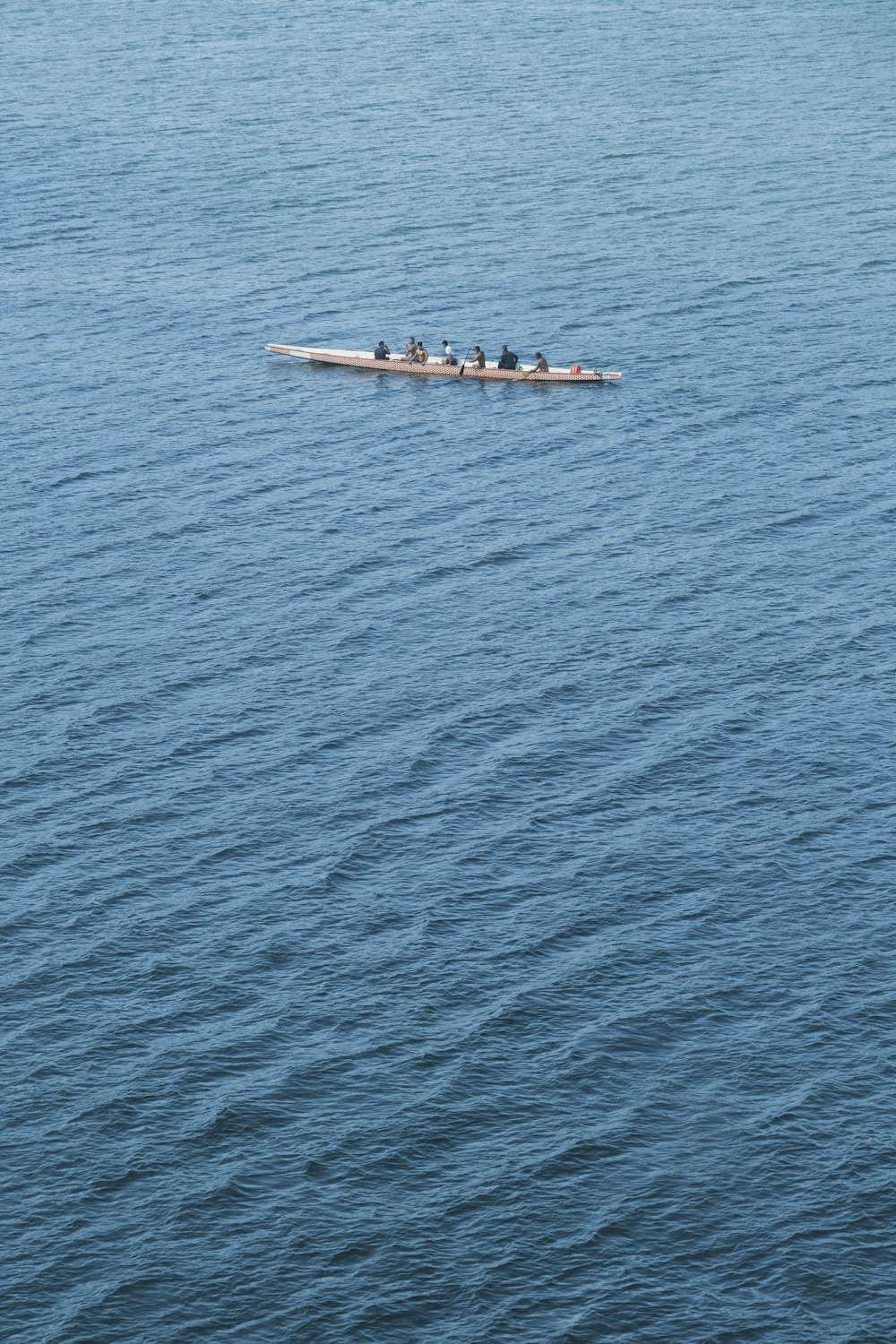 a row boat with four rowers in the middle of a body of water