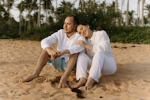 a man and a woman are sitting on the sand