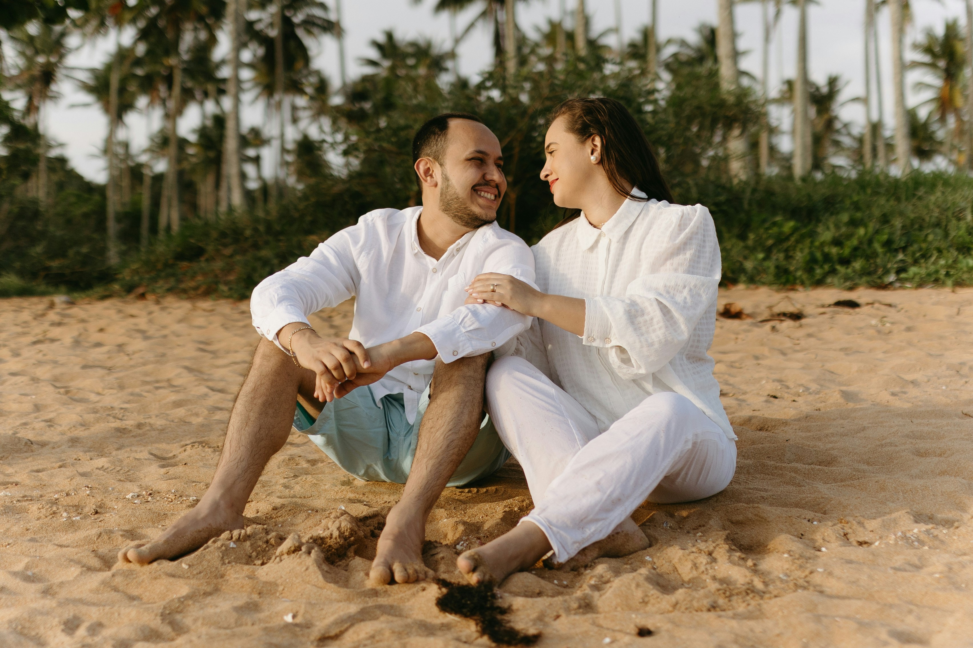 Chilean couple smiling together on tropical beach, bright sunlight, happy relaxed expressions