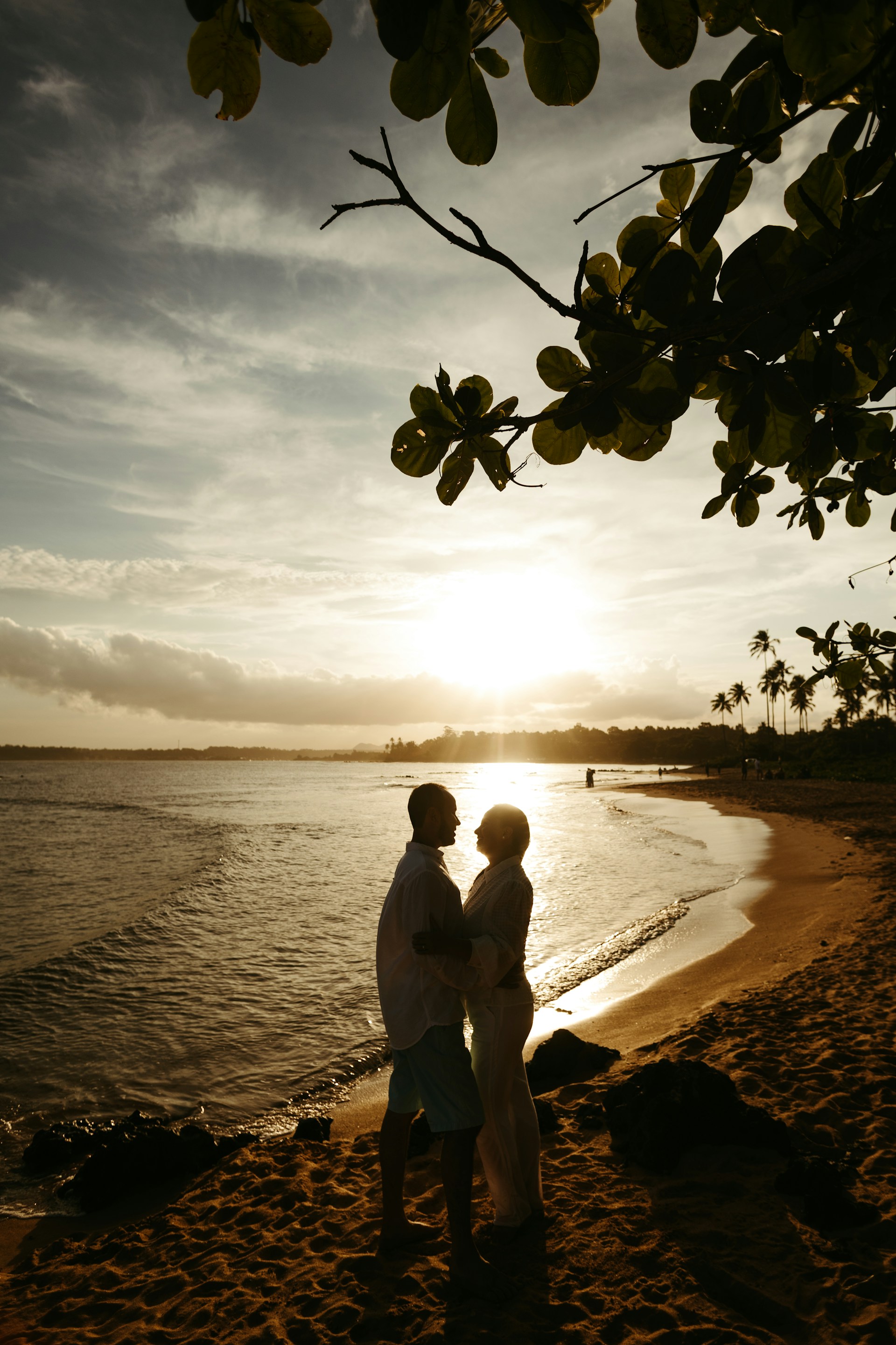 a couple of people standing on top of a sandy beach
