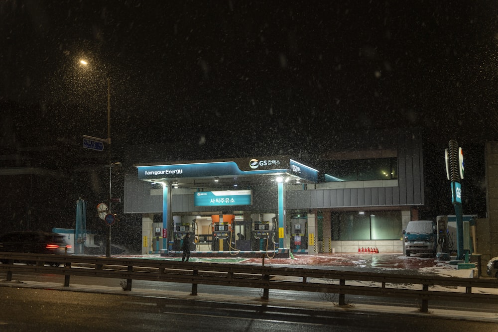 a gas station at night with snow falling on the ground