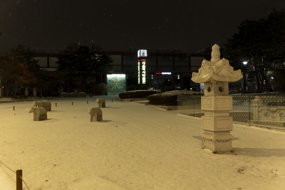 a snow covered park at night with a clock tower in the background