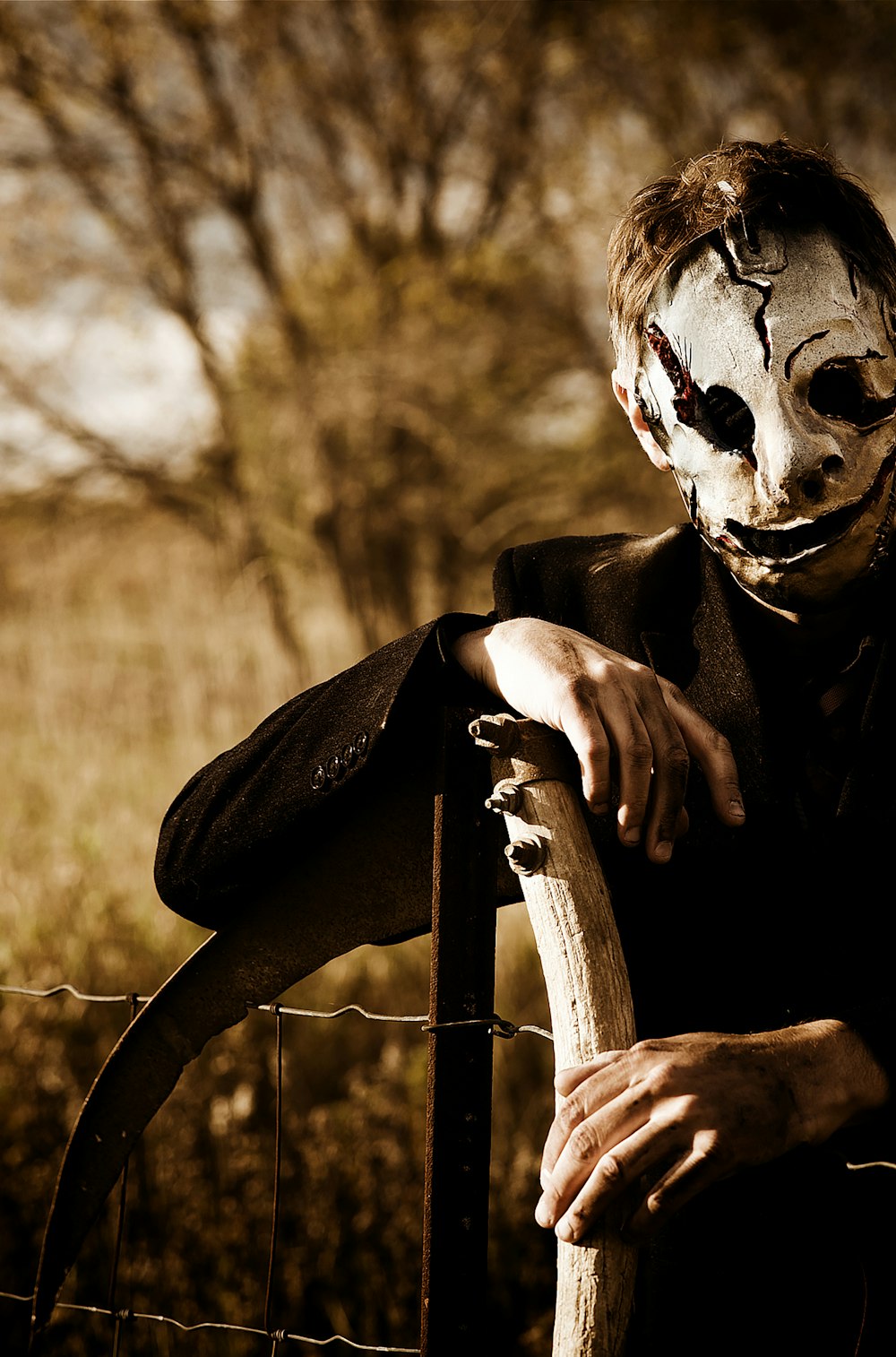 a man in a scary mask leaning on a fence