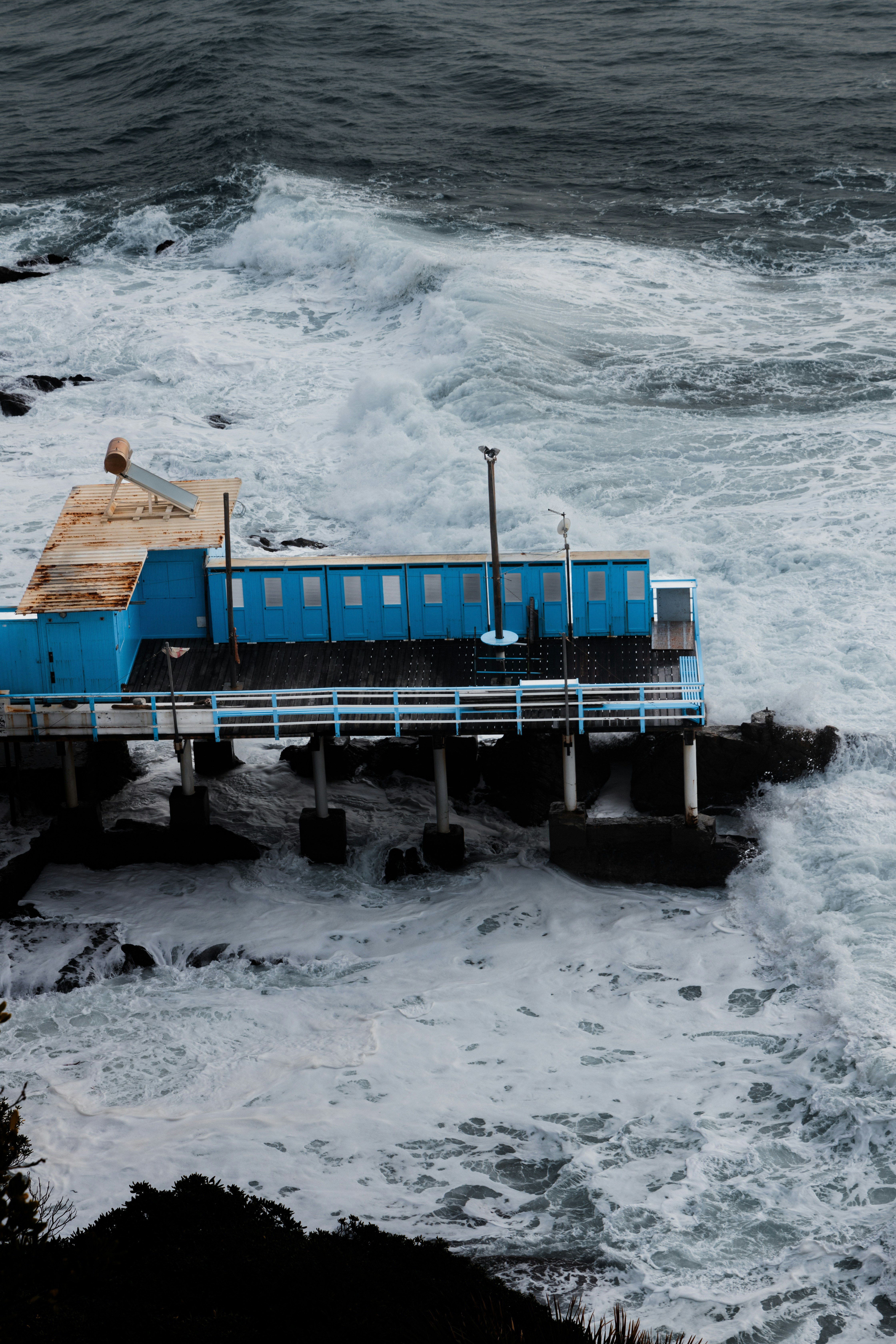 a blue box sitting on top of a pier next to the ocean