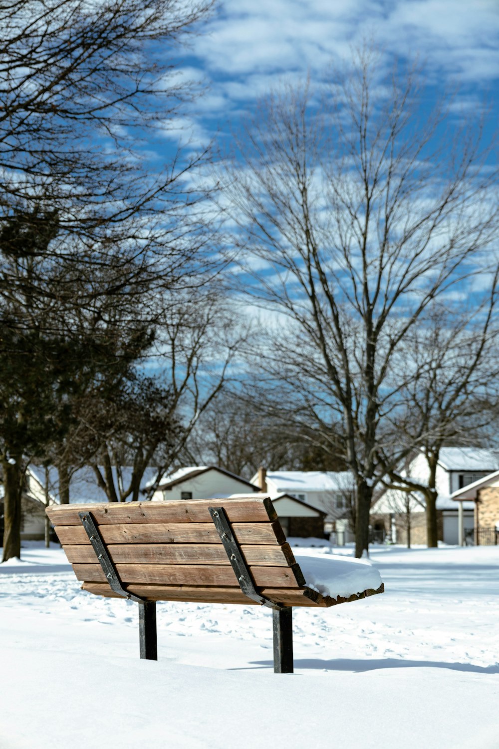 a wooden bench sitting in the middle of a snow covered park