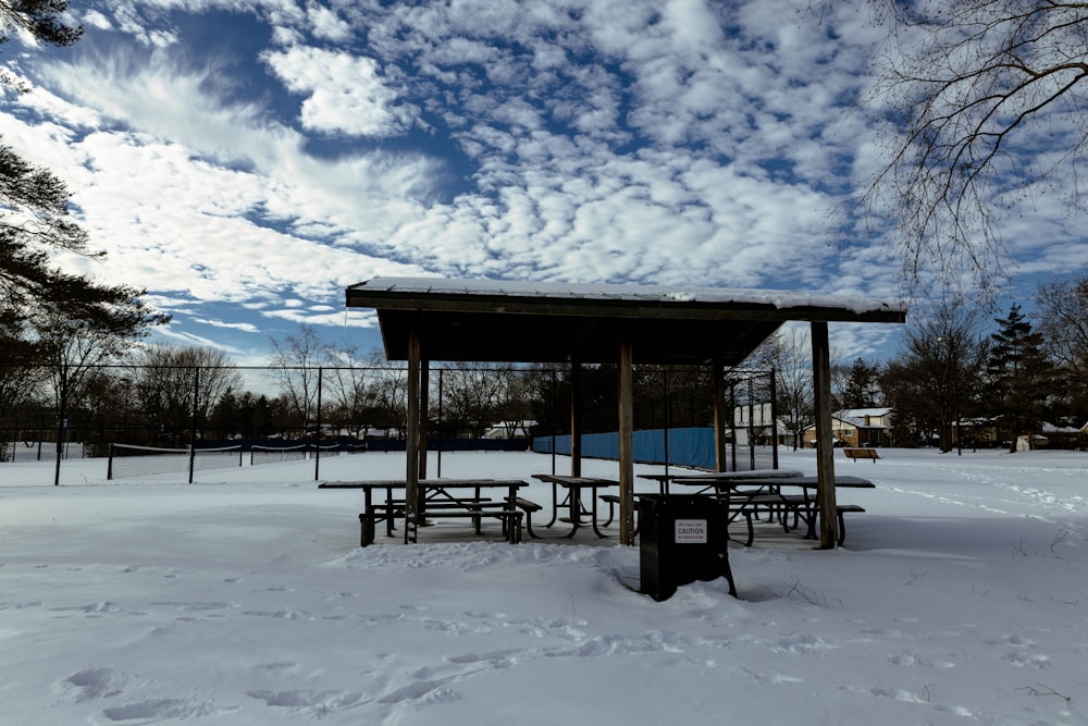 a covered picnic area in the middle of a snowy field
