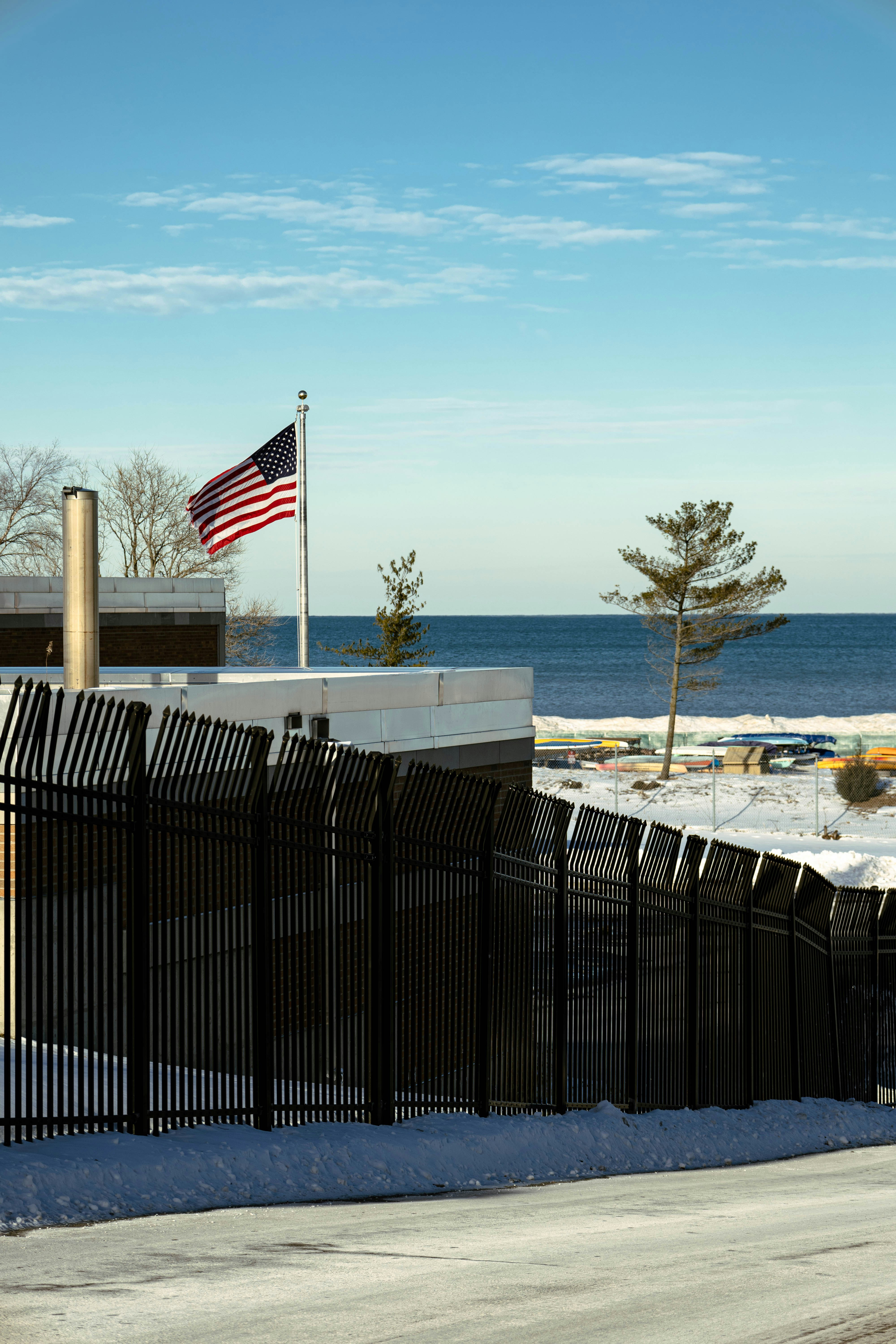 an american flag flying over the ocean next to a fence