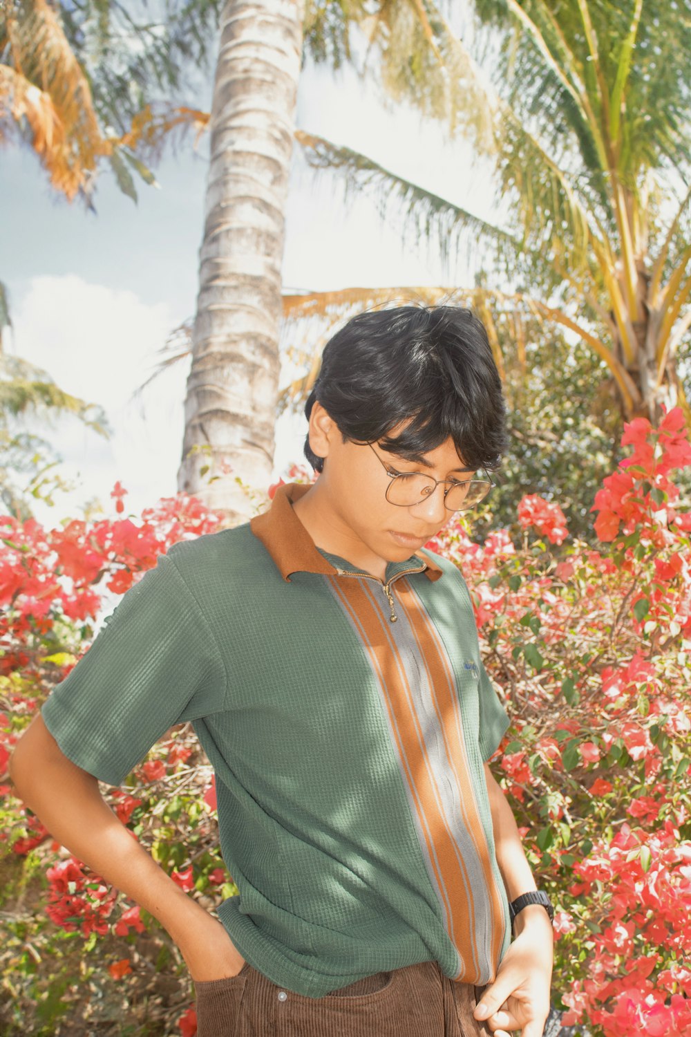 a young man standing in front of a flower garden