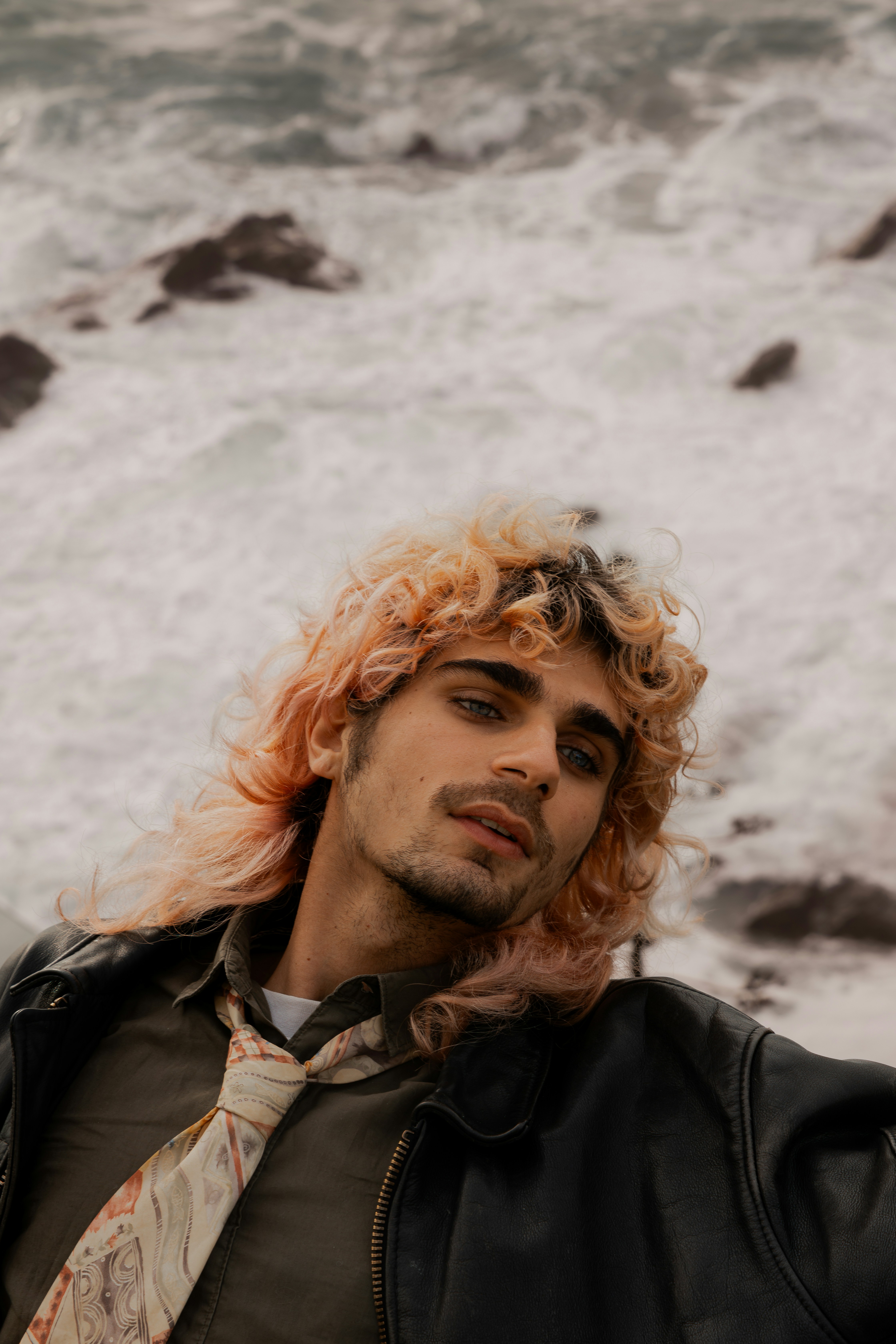 a man with red hair wearing a leather jacket and tie