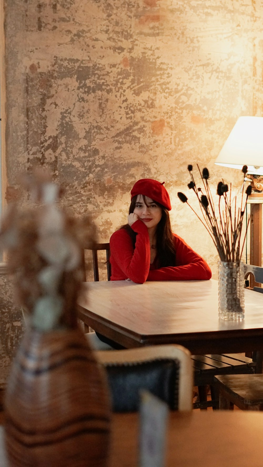 a woman sitting at a table with a red hat on