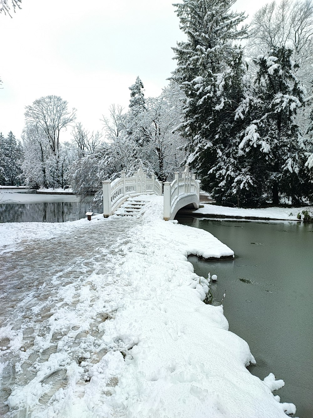 eine Brücke über einen Fluss mit Schnee auf dem Boden