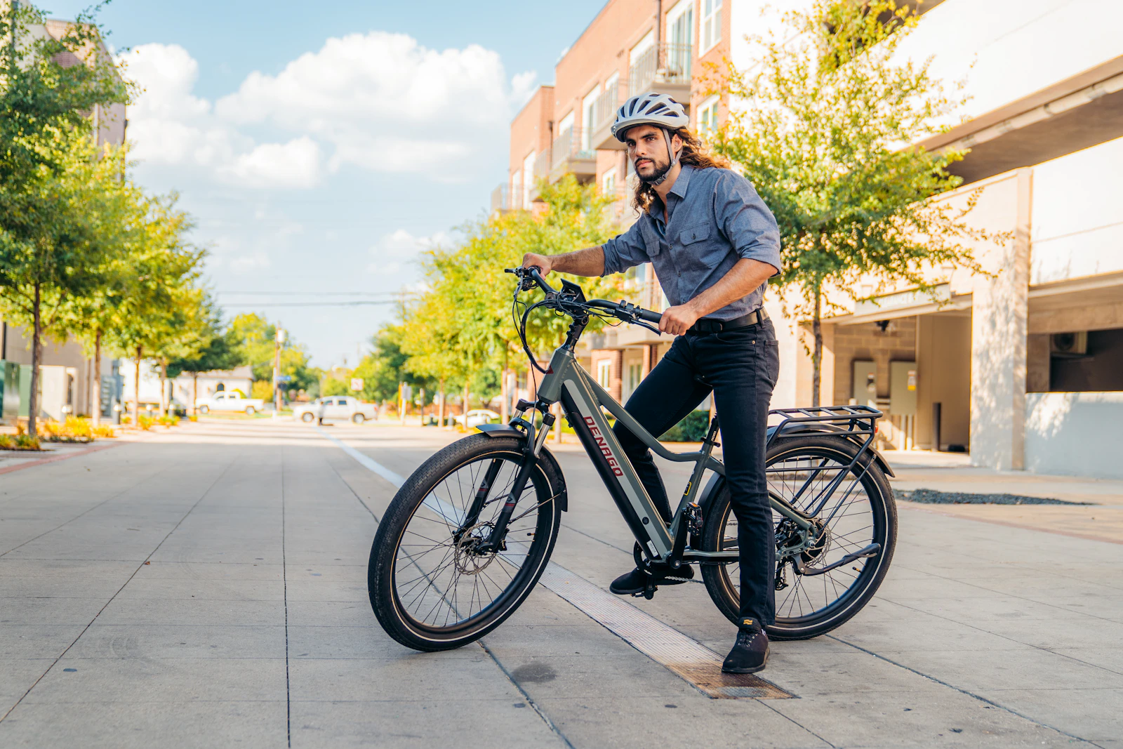 Helmeted rider standing with an electric commuter bicycle on a city street