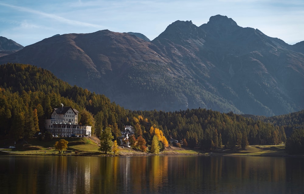 a house on a lake surrounded by mountains