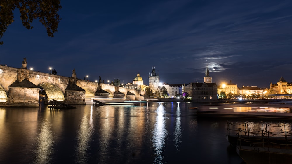 a night view of a river with a bridge and buildings in the background