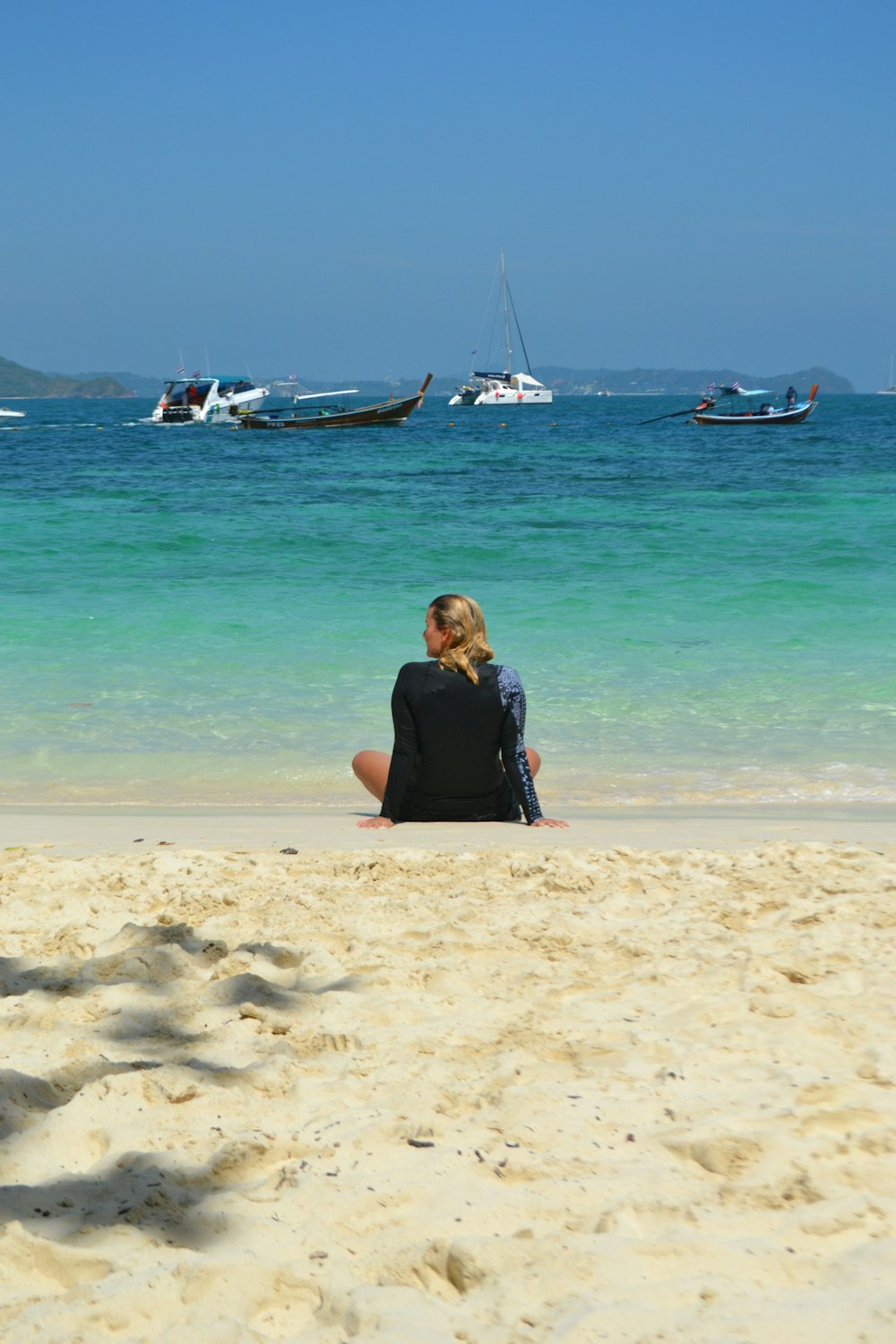 a woman sitting on a beach next to the ocean