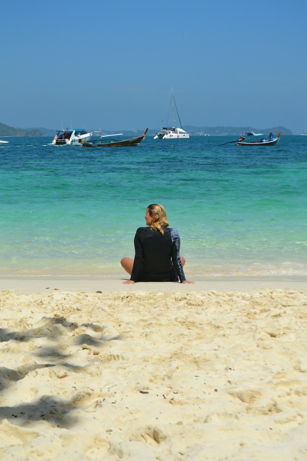 eine Frau sitzt an einem Strand am Meer