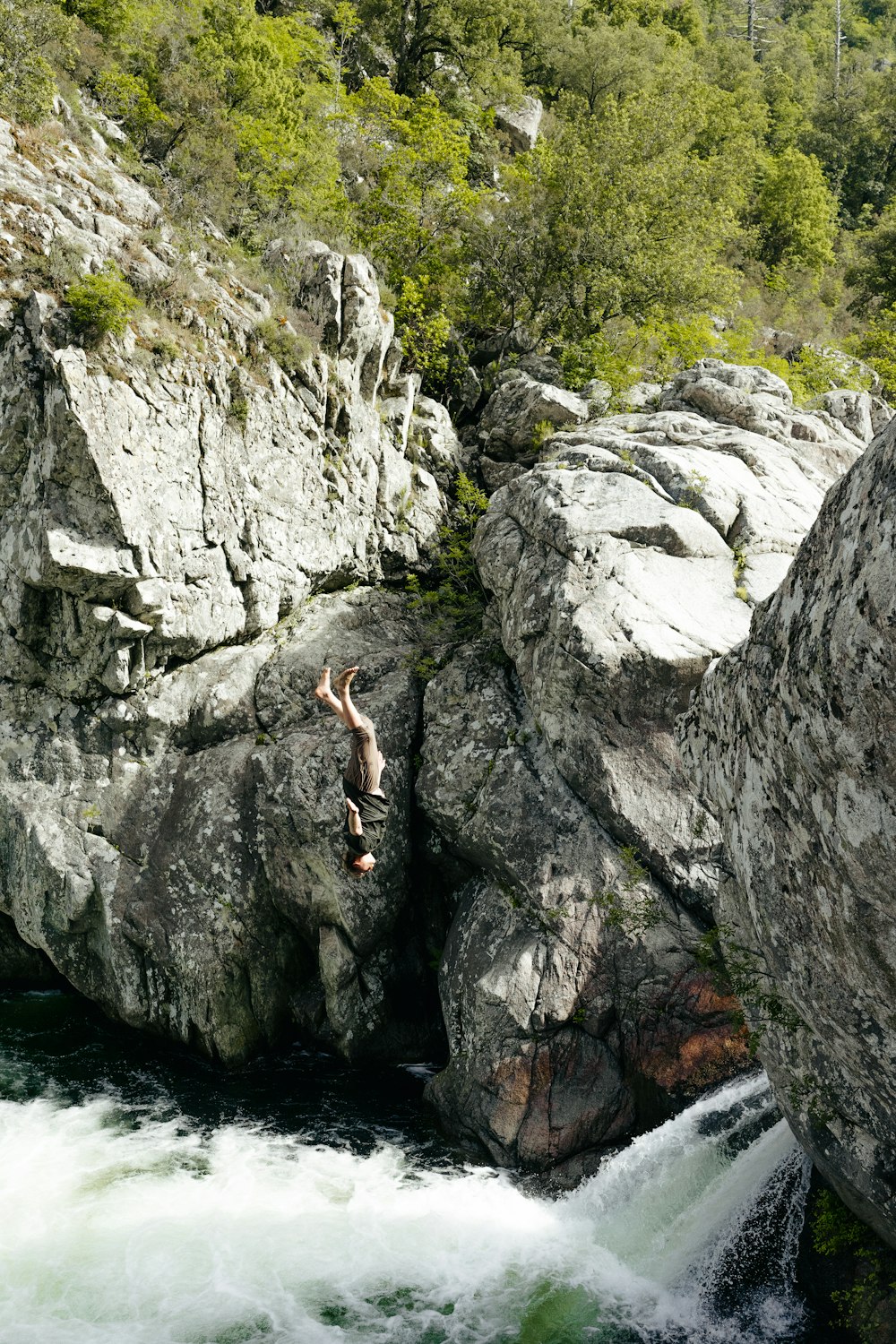 a man jumping off a cliff into a river