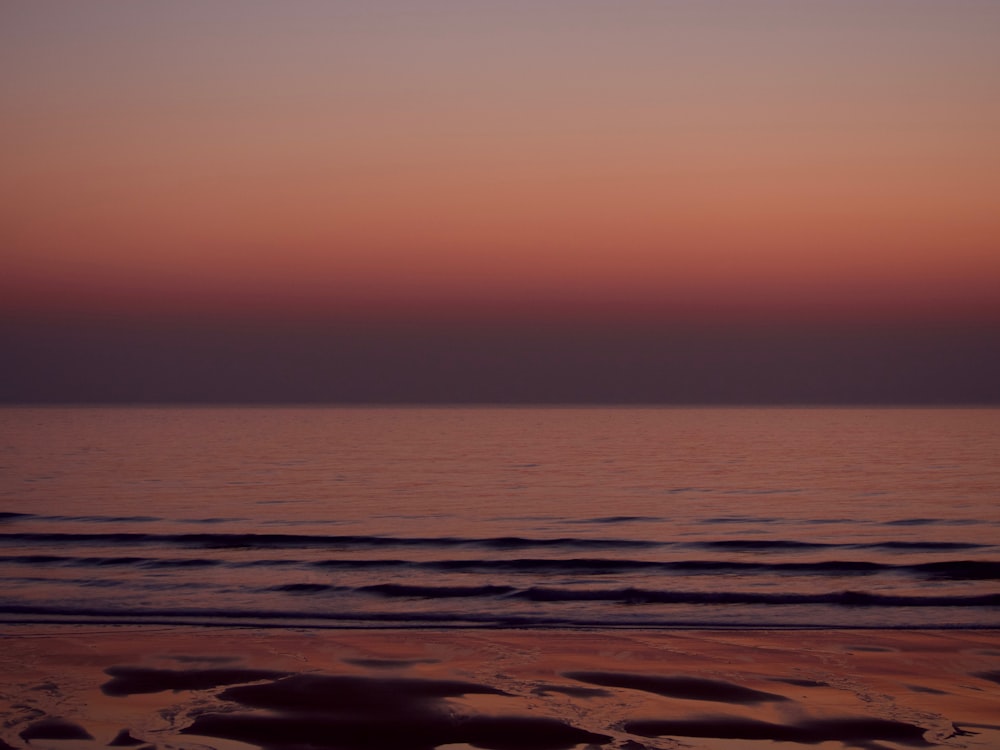 the sun is setting over the water at the beach