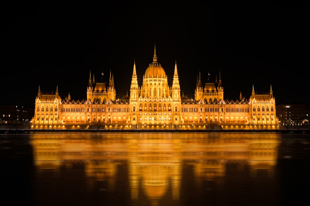 a large building lit up at night with a reflection in the water