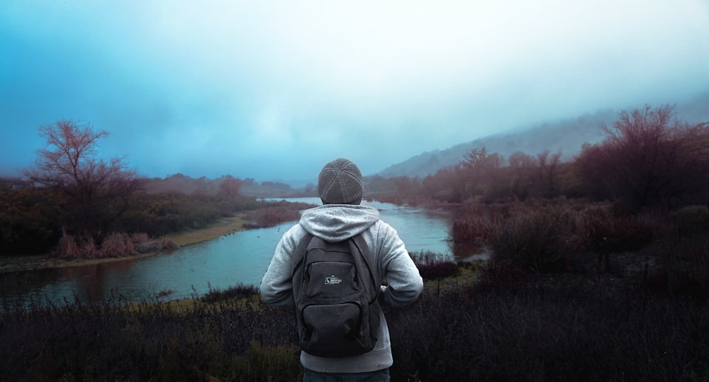 a person with a backpack standing in front of a body of water
