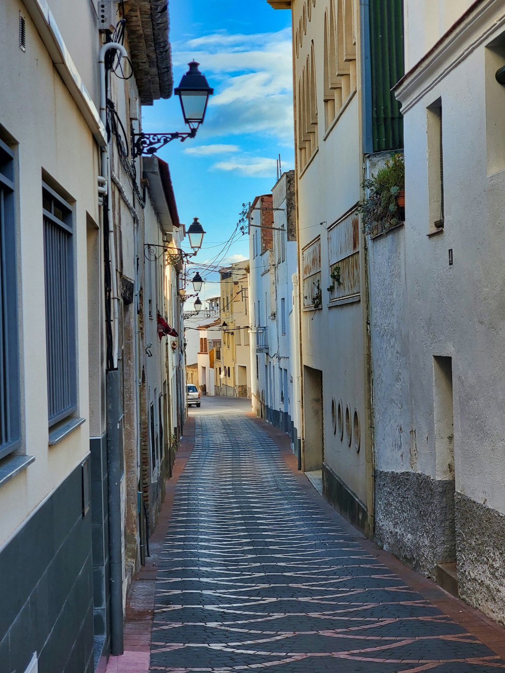 a narrow street with a lamp on the side of it