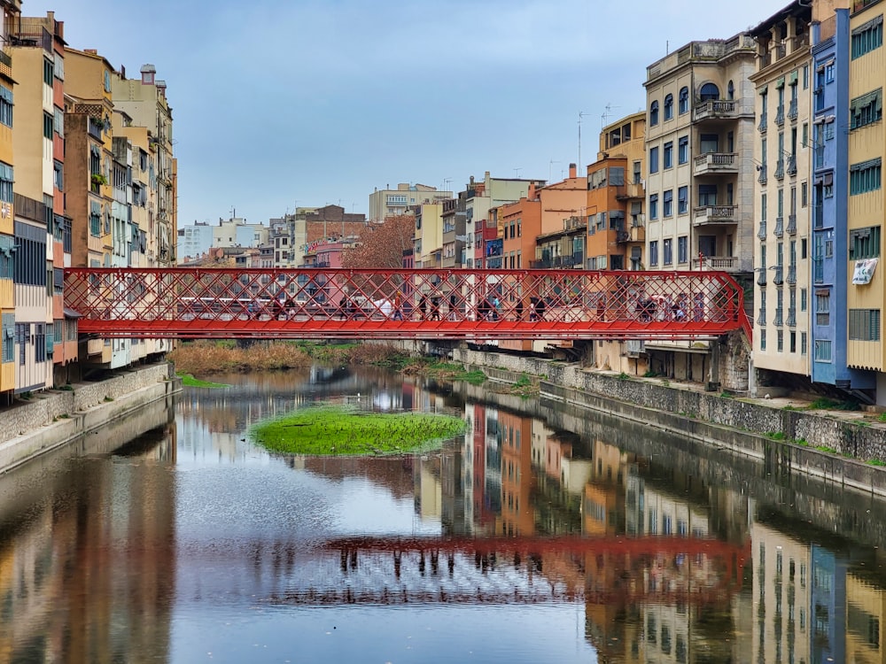 a red bridge over a river in a city