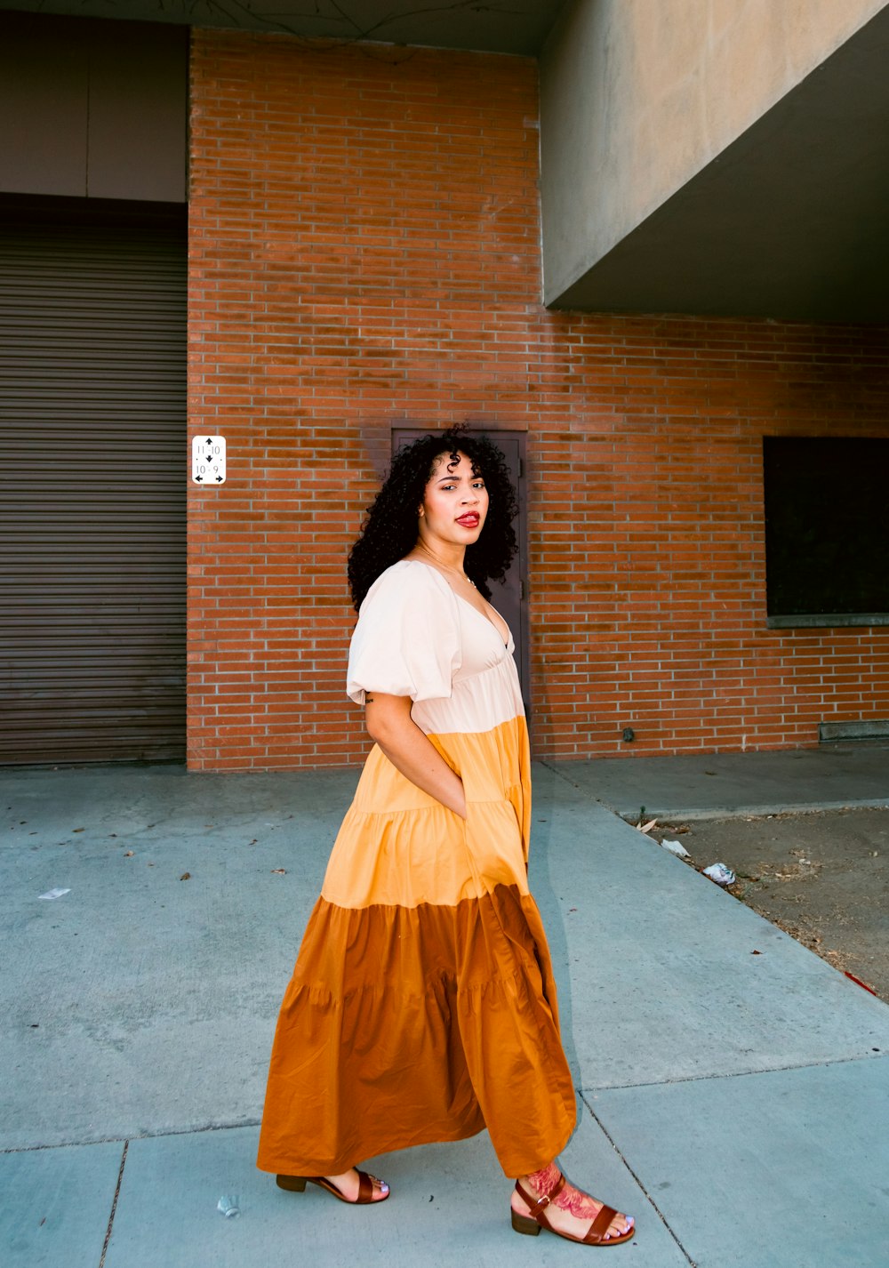 a woman standing on a sidewalk in front of a brick building