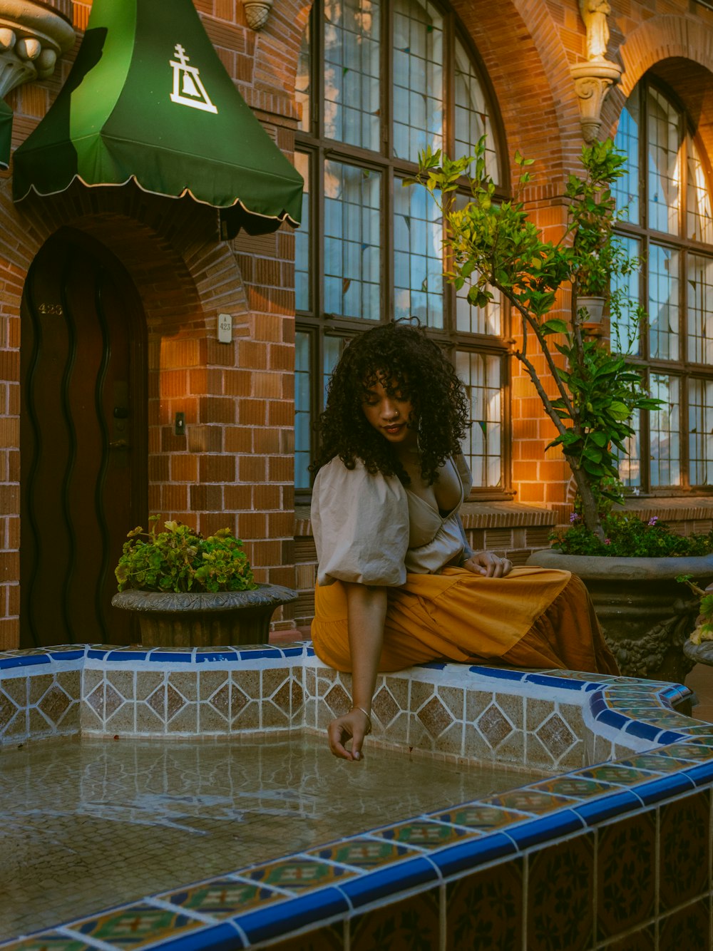 a woman sitting on top of a fountain in front of a building